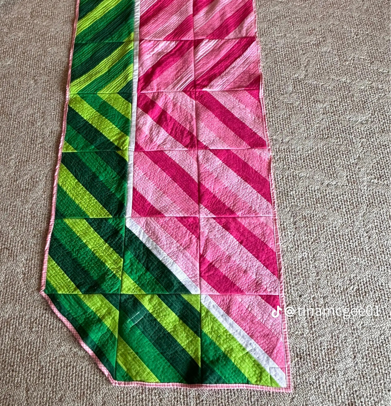 Colorful quilt with green and pink patterns on a beige surface